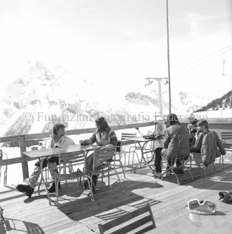 Personen auf Restaurantterrasse, Schlepplift im Hintergrund
