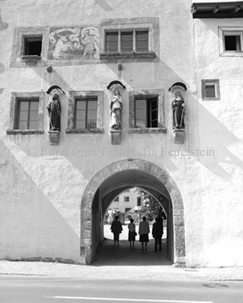 Fassade und Torgang beim Kloster Sankt Johann mit Fresko und Heiligenstatuen, Personen im Gang