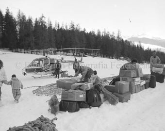 Verladen von Kisten und Koffern, Helikopter im Schneefeld, viele Personen