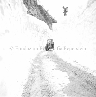 Schneeräumung auf der Strasse nach Lawine mit Flachbagger, Strasse von Schneemauern gesäumt