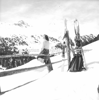 Skitourengängerin auf Zaun, Ski im Schnee mit Rucksack