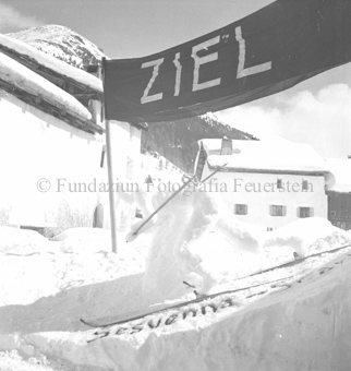 Zielbanner in S-charl, Ski im Schnee und Inschrift «Sesvenna - Scarl»