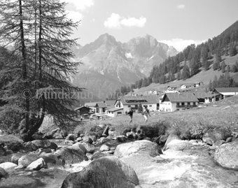 Wanderer neben Bach, Dorf S-charl im Hintergrund