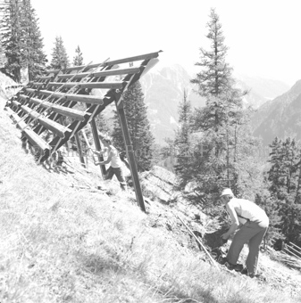 Bau von Lawinenschutz aus Stahl mit zwei Arbeitern am Hang