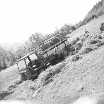 Bauern beladen motorisierten Heuwagen am Hang