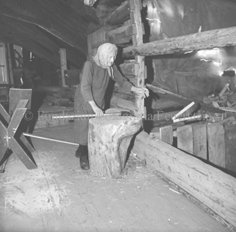 Alte Bäuerin mit Scheitstock und Axt