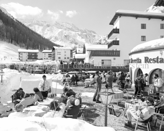 Personen zu Tisch vor Restaurant «Silvretta», verschneite Landschaft