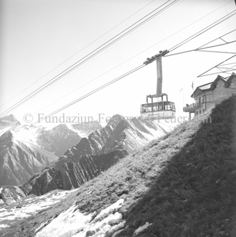 Luftseilbahngondel vor Berglandschaft, zum Teil schneebedeckt, bei Bergstation