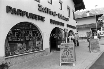 Personen vor Schaufenster, Zollfreie Parfumerie, Bijouterie und Spirituosen, Werbetafel