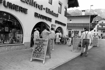 Personen vor Schaufenster, Zollfreie Parfumerie, Bijouterie und Spirituosen, Werbetafel