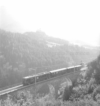 Zug der Rhätischen Bahn auf Viadukt, Wald und Berglandschaft im Hintergrund