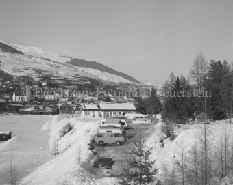 Verschneiter Fussballplatz, Wohnwagen und Campingbusse, Kirche im Hintergrund