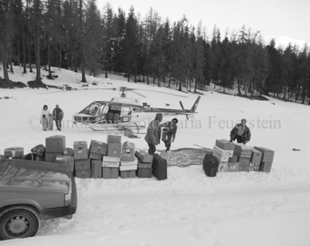 Verladen von Kisten und Koffern, Helikopter im Schneefeld, viele Personen