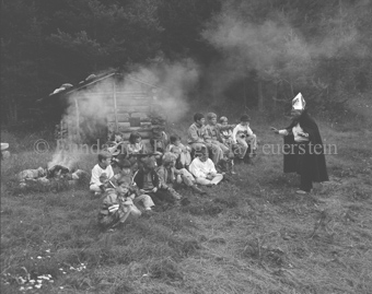 «Märchenprinz», Mann im Zaubererkostüm mit Kindergruppe bei Lagerfeuer bei Waldhütte
