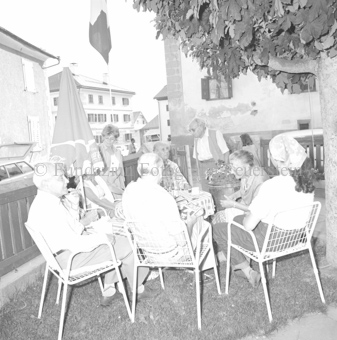 Personen in Stühlen im Garten unter Baum