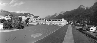 Sportplatz und Schulhaus, Berglandschaft im Hintergrund