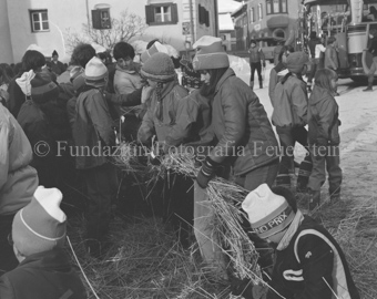 L'Hom Strom, Personen bauen Strohmann auf Dorfplatz