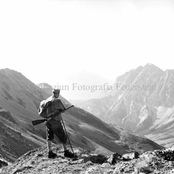 Jäger mit Gewehr, Berglandschaft im Hintergrund