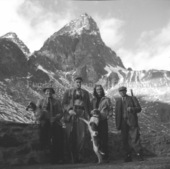 Drei Jäger mit Gewehren, Mädchen und zwei Hunden vor Berglandschaft
