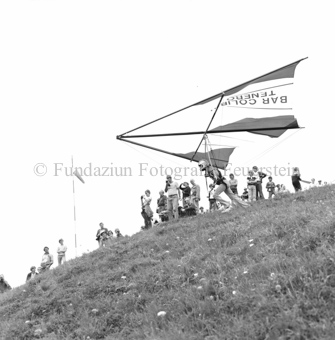 Hängegleiterflieger startet von Wiese mit Zuschauern