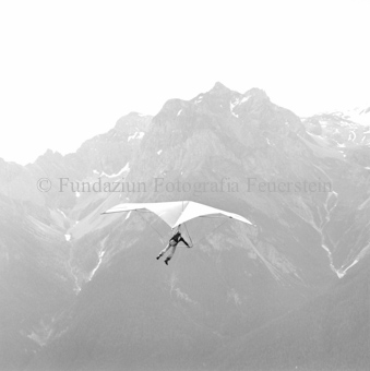 Hängegleiterflieger in der Luft, Berge im Hintergrund
