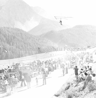 Hängegleiterflieger über dem Boden auf dem Berg, Zuschauer mit Autos