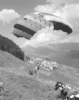 Gleitschirmflieger beim Start, Dorf im Hintergrund