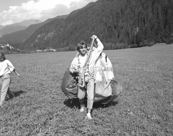 Gleitschirmflieger nach der Landung mit Schirm, Dorf und Wald im Hintergrund