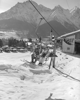 Skifahrer und Snowboarder auf Sessellift bei Talstation Ftan