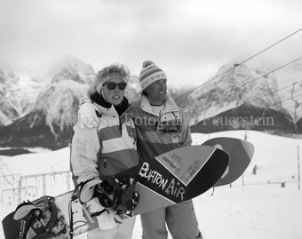 Zwei Snowboarder mit Brett in der Hand posieren für Foto, Berglandschaft im Hintergrund