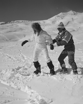 Mann hilft Frau auf Snowboard