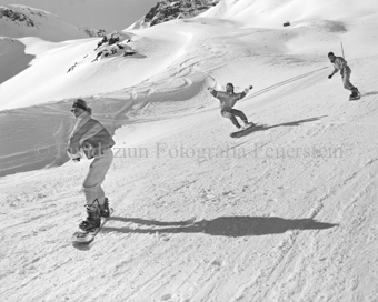 Drei Snowboarder auf Piste