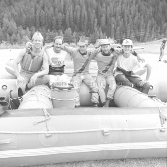 Fünf Schlauchbootfahrer im Boot auf dem Trockenen, Wald im Hintergrund