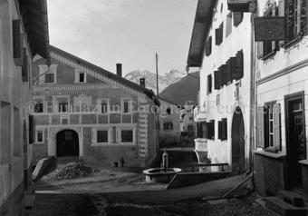 Gasse mit Brunnen im Dorf bei «Pensiun-Passants, Turists, Crusch Alba», Fassaden mit Sgraffito
