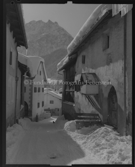 Dorfgasse im unteren Dorfteil von Scuol mit Piz Pisoc