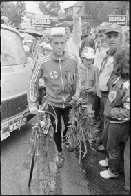 Radrennfahrer mit Rennrad und Blumen, umgeben von Fans