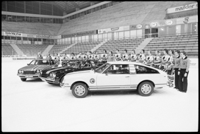 Gruppenfoto der Eishockeymannschaft vom Schlittschuh-Club Bern mit Autos auf dem Eisfeld