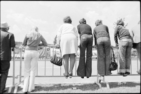Zuschauerinnen und Zuschauer hinter Absperrung das Radrennen verfolgend