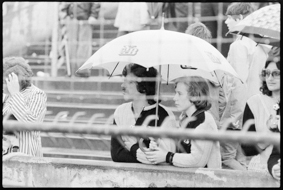 Paar mit YB-Fanjacken und YB-Regenschirm auf Zuschauertribüne