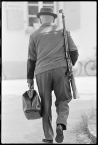 Mann mit Gewehr und Aktenmappe