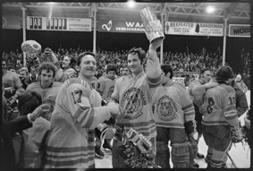 Jubelnde Spieler mit Pokal auf dem Eisfeld