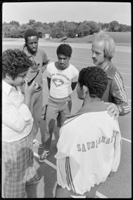 Trainer unterhält sich mit vier jungen Leichtathleten