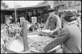 Männer in Kleidung von früher beim Papier schöpfen aus grossem Holz-Bottich, im Hintergrund Bühne mit Musikern «Maxim Cham», rechts Restaurant Thurm und Papeterie «Paputik»