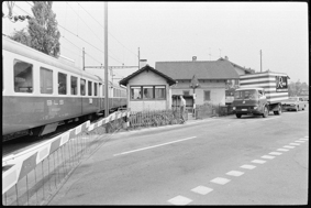 Bahnübergang mit vorbeifahrendem BLS-Zug, Bahnhwärterhäuschen, wartenden Autos
