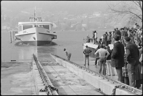 Das Schiff MS Petersinsel an Seilwinde befestigt gleitet auf Schienen in den Bielersee, daneben Schaulustige
