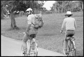 Mann mit Rucksack und Picknick und Frau mit grosser Sonnenbrille auf Velofahrt in ländlicher Umgebung