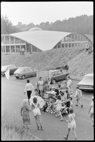 Umzug mit bunt geschmückten Wagen zum Thema «Baden», oben im Bild das neu erstellte Hallenbad 
