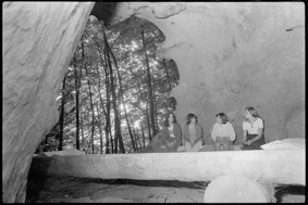 vier junge Frauen in Höhle auf Holzbänken sitzend