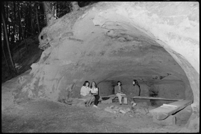 vier junge Frauen in Höhle auf Holzbänken sitzend