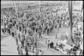 Der Aarberger Gemeindepräsident Hans Liechti am Rednerpult vor dem Rathaus, daneben Frauen in Trachten auf einer Bühne, vor ihnen Zuschauende und Fotografen, im Hintergrund Ladengeschäfte und festlich beflaggter Stadtplatz